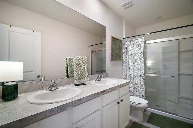 a bathroom with a double vanity sink toilet and shower