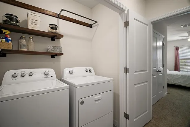 a view of washer and dryer with bathroom in the background