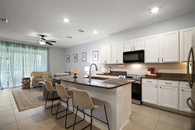 a kitchen with stainless steel appliances granite countertop a stove top oven a sink dishwasher a dining table and chairs with wooden floor