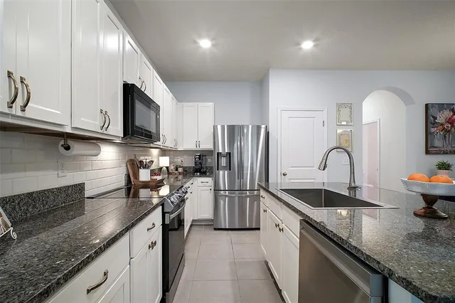 a kitchen with granite countertop a sink stainless steel appliances and cabinets