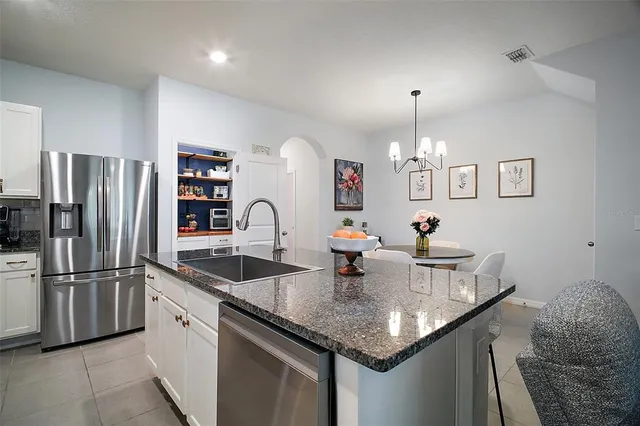 a kitchen with granite countertop a sink stainless steel appliances and chandelier