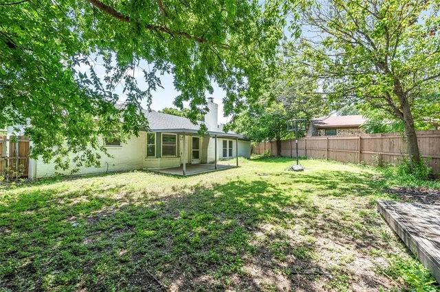 a view of a backyard with large trees and wooden fence