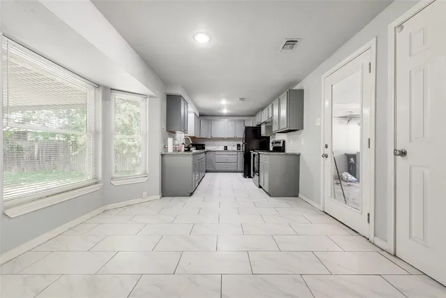 a large white kitchen with stainless steel appliances granite countertop a refrigerator and a sink