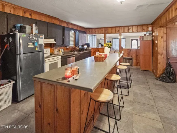 a kitchen with stainless steel appliances granite countertop a stove a refrigerator a kitchen island and chairs in it