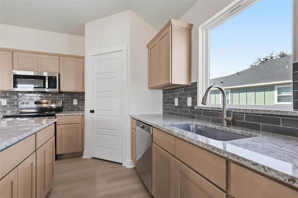 472 Peace Lily Way Tolar, TX 76476 - Photo 11 of 40 a kitchen with granite countertop a sink a stove top oven and cabinetry