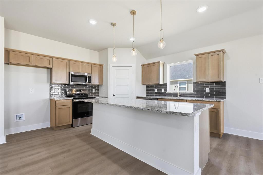 472 Peace Lily Way Tolar, TX 76476 - Photo 8 of 40 a kitchen with kitchen island granite countertop a sink cabinets and stainless steel appliances