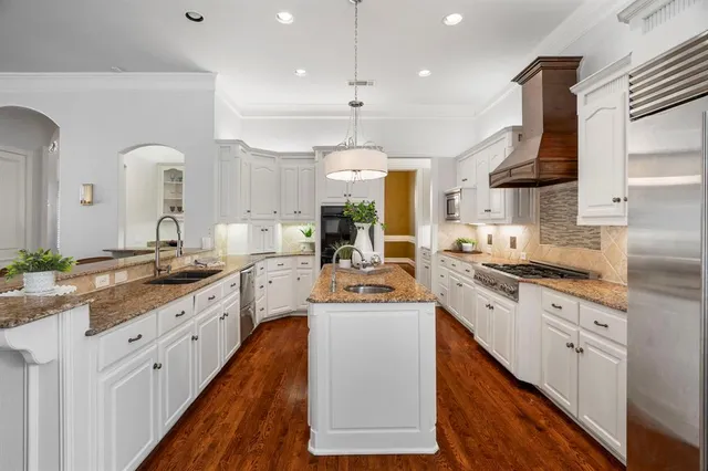 a open kitchen with stainless steel appliances granite countertop a stove top oven a sink dishwasher and white cabinets with wooden floor