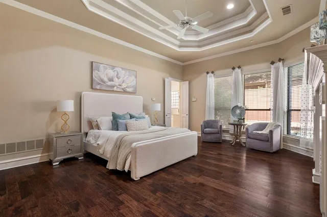 a spacious bedroom with a bed couch and a large window with wooden floor