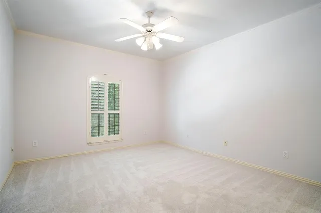 an empty room with chandelier fan and windows