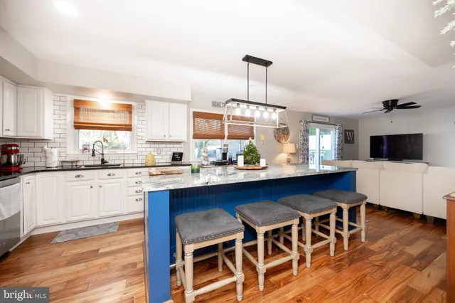 a kitchen with stainless steel appliances granite countertop a sink a stove and a wooden floors