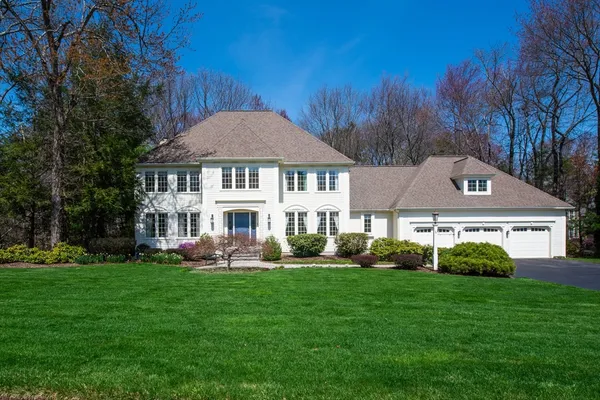 a front view of a house with a garden and trees