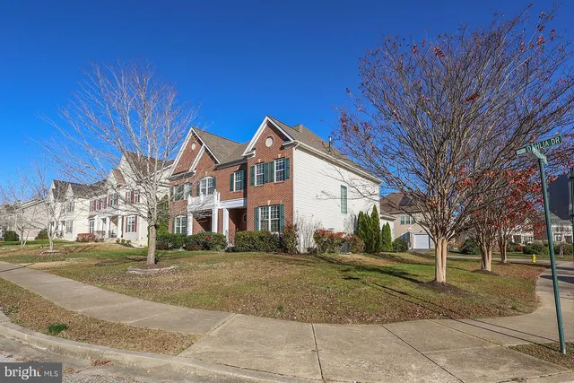 a view of a white house next to a yard with large trees