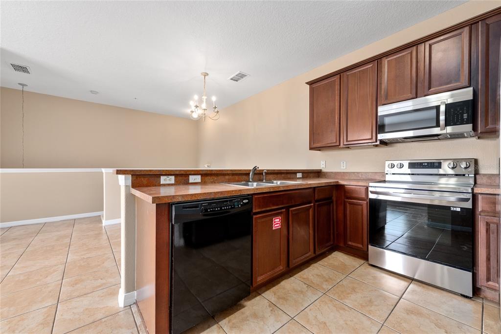 7531 Pellham Way, Unit 77 Kissimmee, FL 34747 - Photo 9 of 28 a kitchen with stainless steel appliances granite countertop a stove and a microwave