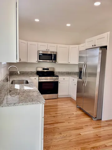 a kitchen with kitchen island granite countertop a refrigerator a sink a stove a microwave and wooden cabinets