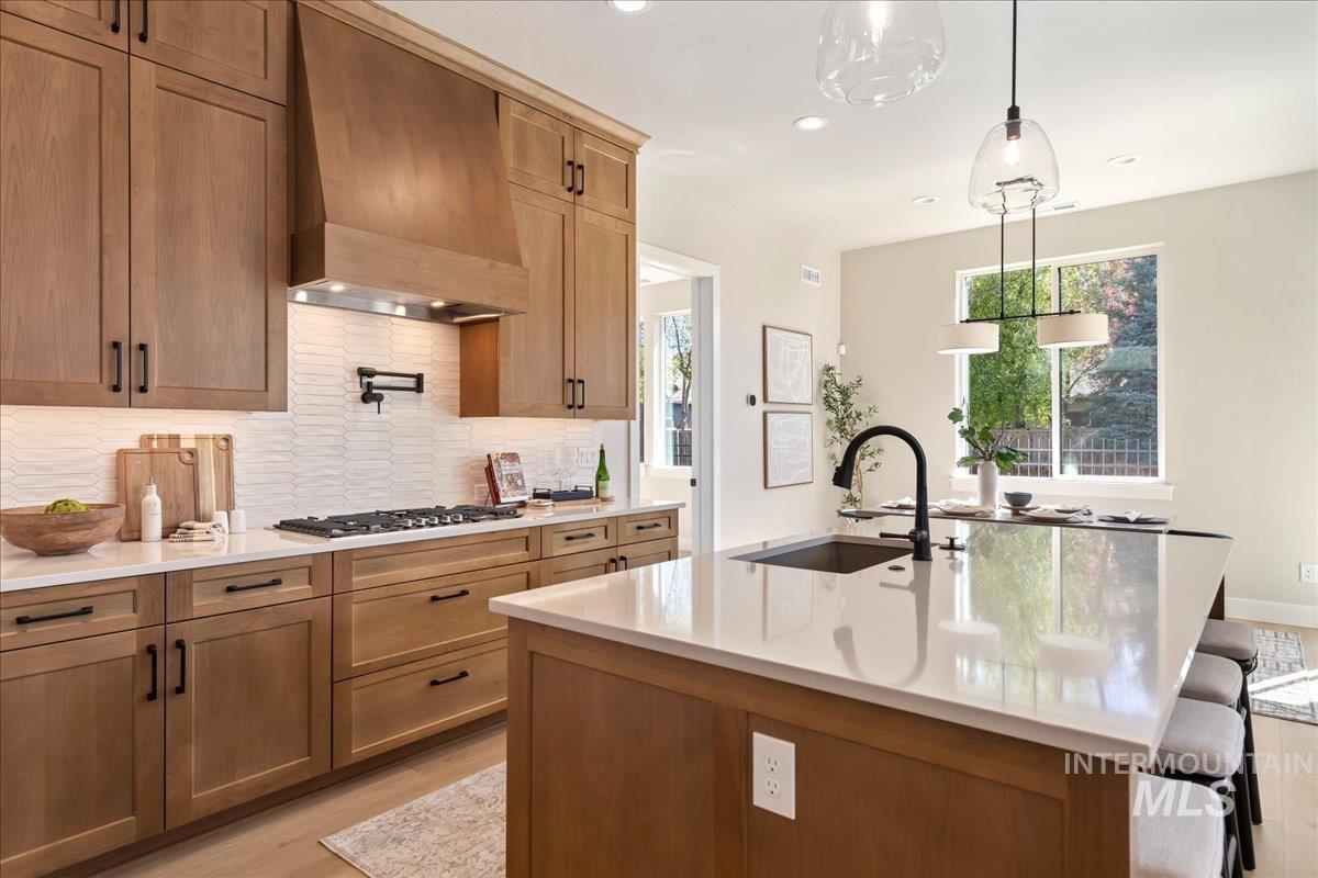 901 West Malbar Street Meridian, ID 83646 - Photo 11 of 33 Kitchen featuring light stone counters, wood finish cabinetry, a center island with sink, a kitchen breakfast bar, and light wood-type flooring