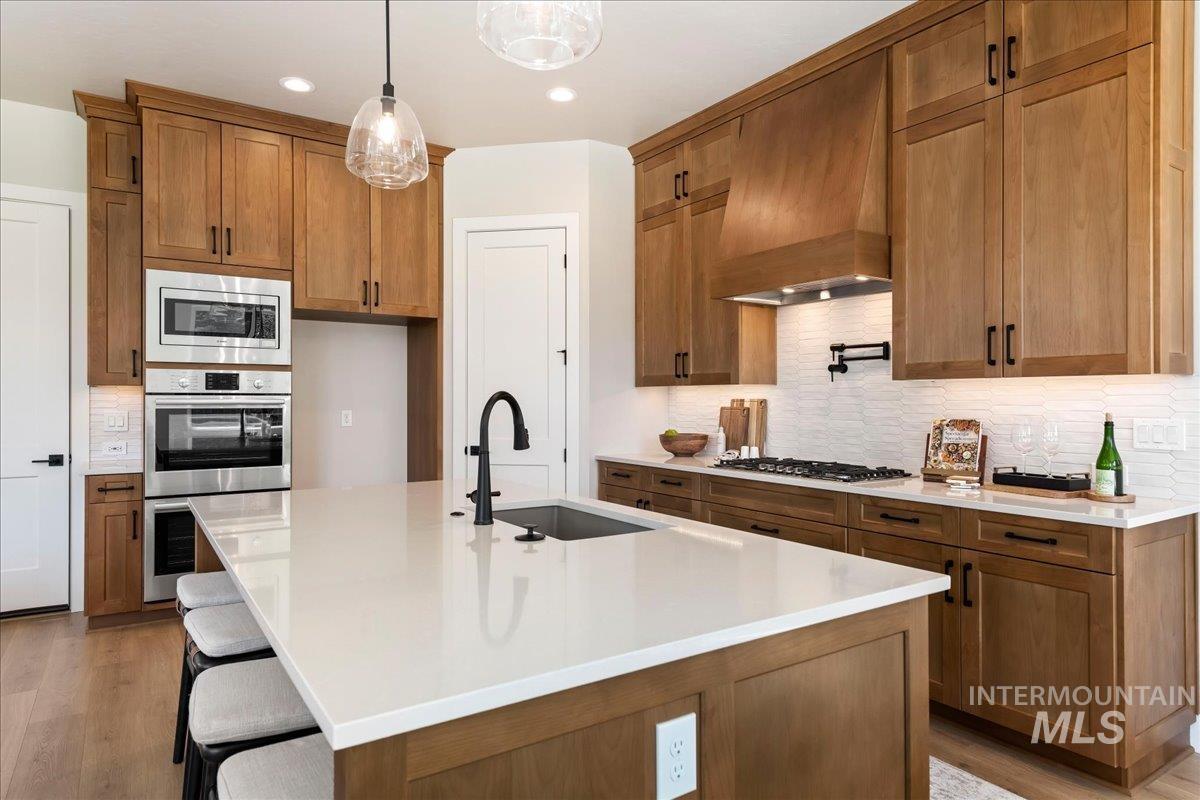 901 West Malbar Street Meridian, ID 83646 - Photo 12 of 33 Kitchen featuring a kitchen bar, a kitchen island with sink, light stone countertops, wood finish cabinetry, and stainless steel appliances