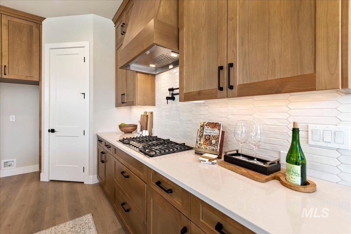 901 West Malbar Street Meridian, ID 83646 - Photo 10 of 33 Kitchen featuring light stone countertops, wood finish cabinetry, backsplash, stainless steel gas stovetop, and light wood-style flooring