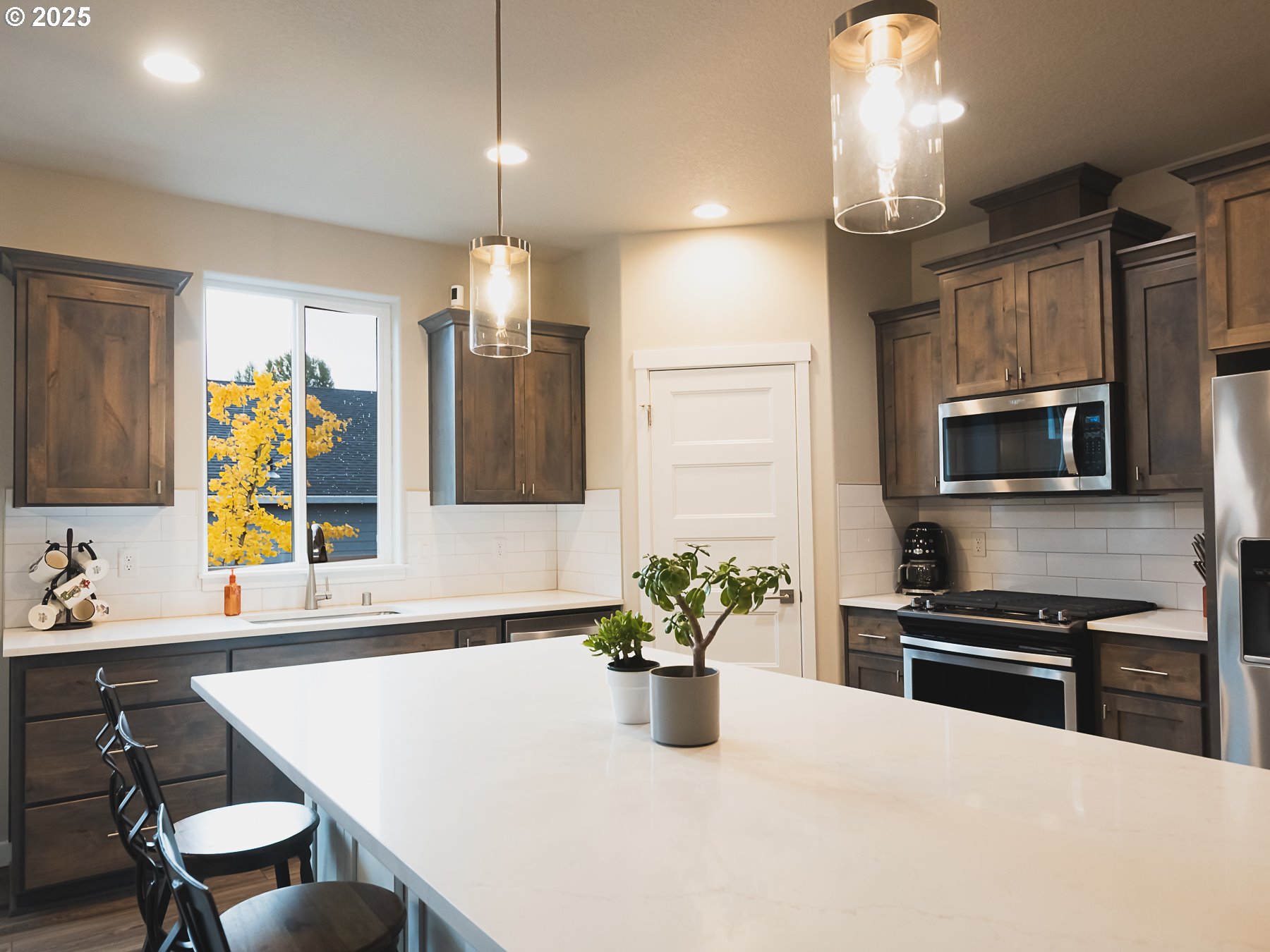 2116 North 3rd Way Ridgefield, WA 98642 - Photo 9 of 40 a kitchen with stainless steel appliances kitchen island granite countertop a sink a stove a microwave a dining table and chairs with wooden floor