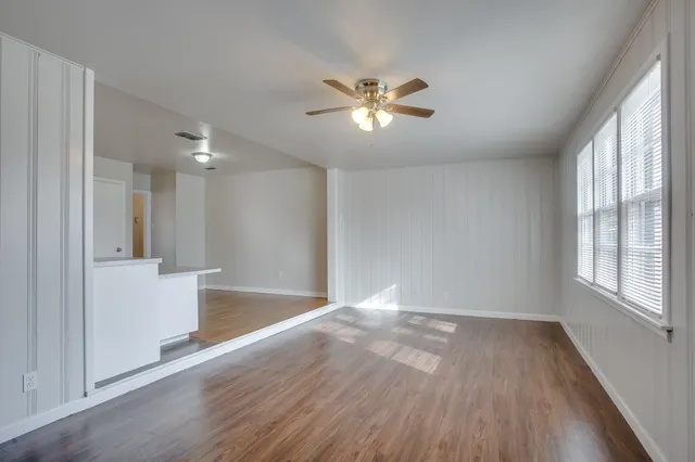a view of empty room with wooden floor and fan