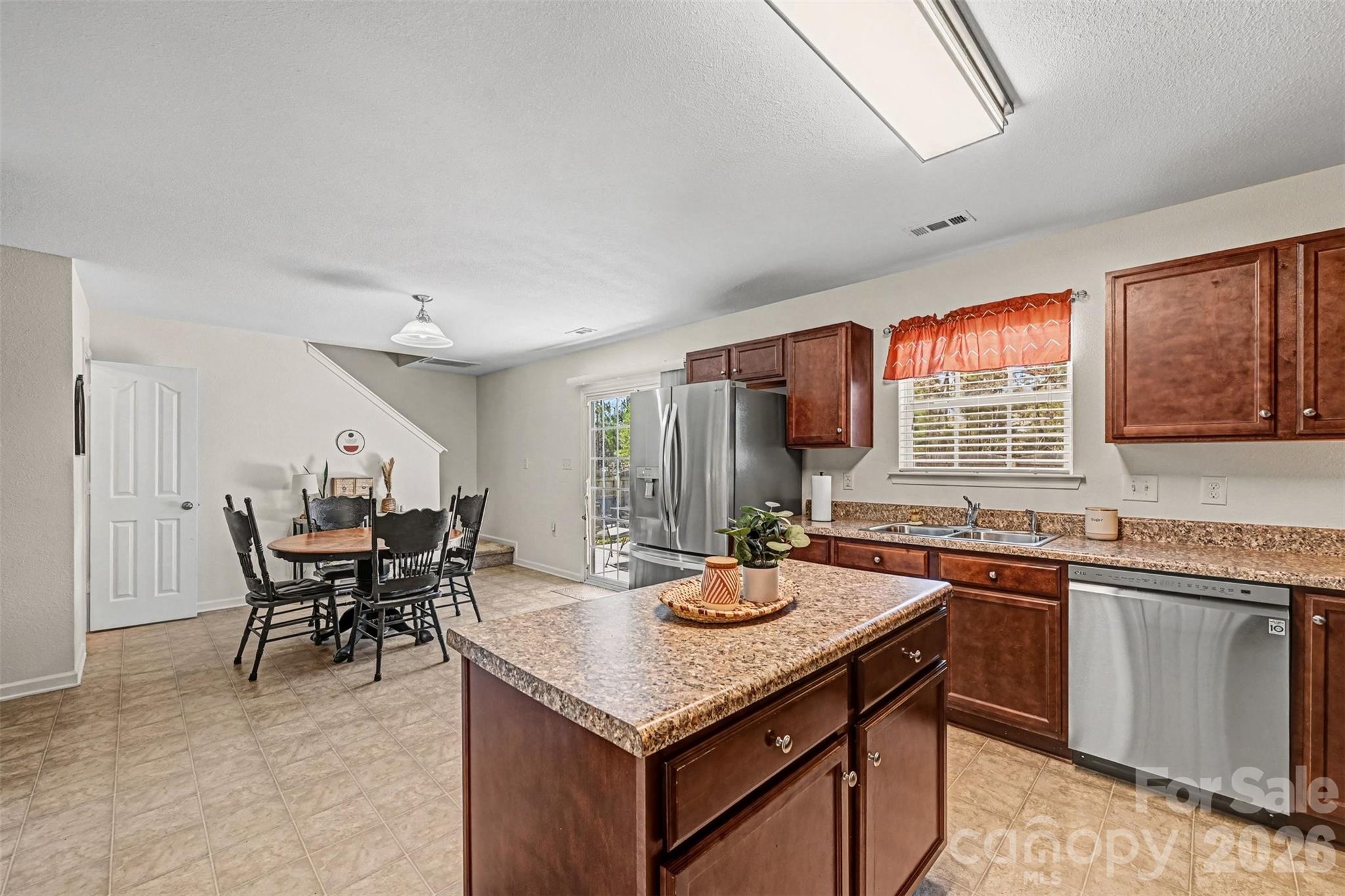 4804 Manchineel Lane Monroe, NC 28110 - Photo 12 of 28 a kitchen with a stove a sink a kitchen island with chairs and wooden cabinets