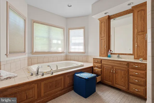 a bathroom with a granite countertop tub sink and mirror