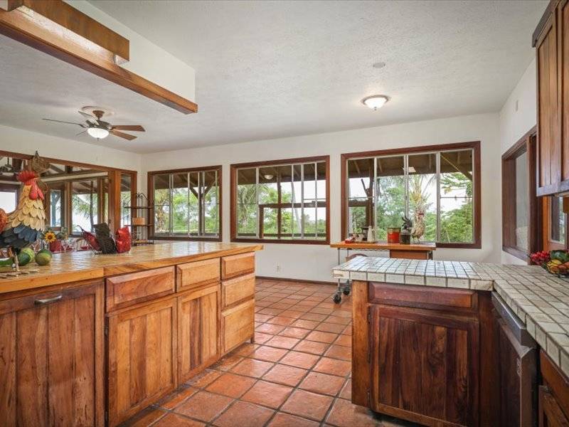 84-5193 Hawaiʻi Belt Road Captain Cook, HI 96704 - Photo 5 of 30 a large kitchen with kitchen island granite countertop a large window cabinets and stainless steel appliances