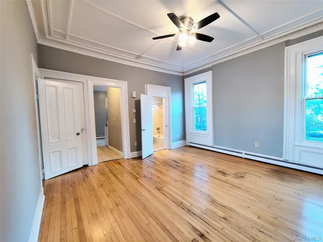 a view of an empty room with window and wooden floor