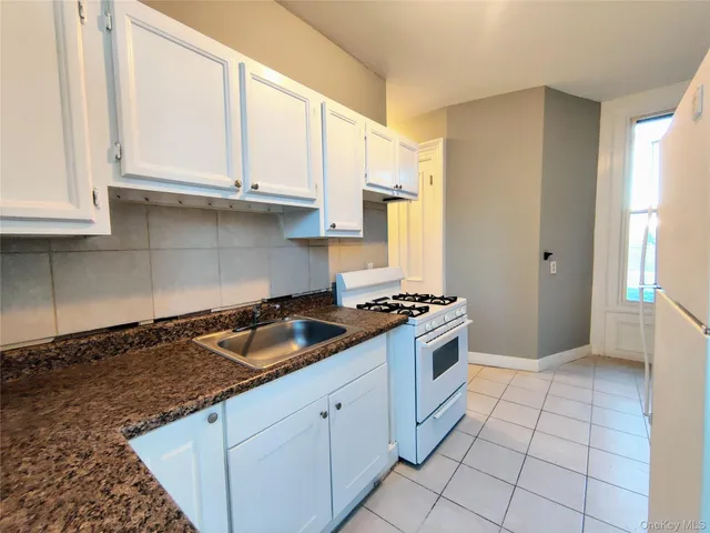 a kitchen with granite countertop a stove sink and cabinets