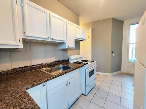 a kitchen with granite countertop a stove sink and cabinets