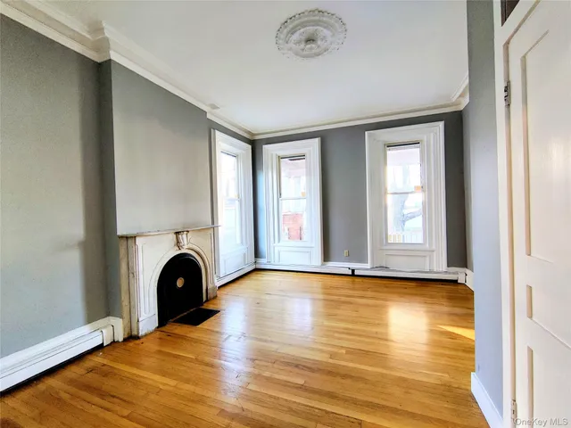 a view of empty room with fireplace and wooden floor