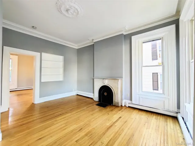 a view of empty room with wooden floor and fireplace