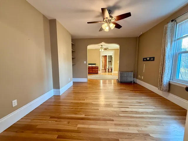a view of an empty room with window and wooden floor