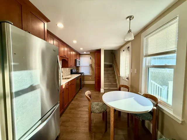 a kitchen with stainless steel appliances a refrigerator a sink a dining table and chairs