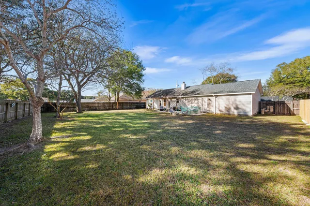 a view of a big house with a big yard and large trees