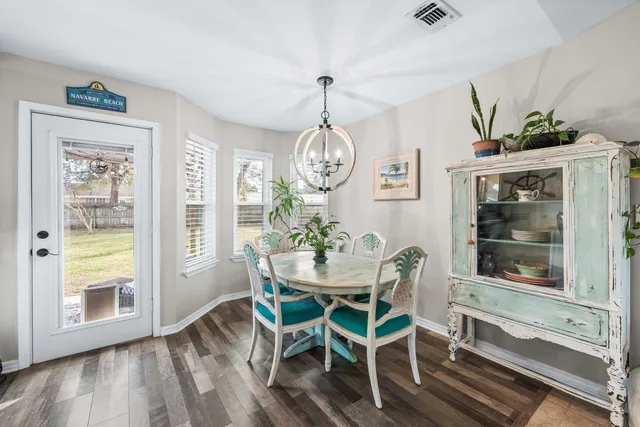 a dining room with wooden floor a chandelier a wooden table and chairs