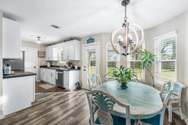 a kitchen with granite countertop stainless steel appliances a table and chairs in it