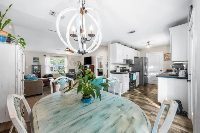 a kitchen with stainless steel appliances granite countertop a refrigerator a sink dishwasher a dining table and chairs with wooden floor