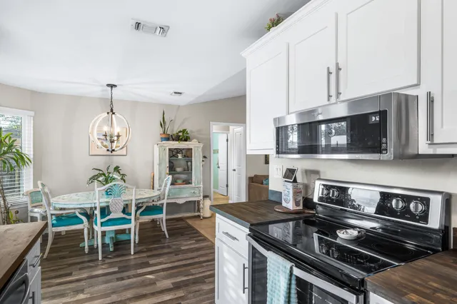 a kitchen with stainless steel appliances granite countertop a stove top oven a dining table and chairs with the wooden floor