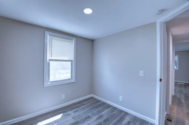 an empty room with wooden floor closet and windows