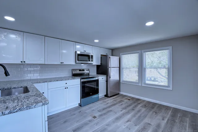 a kitchen with stainless steel appliances granite countertop a stove a sink dishwasher and a refrigerator with wooden floor