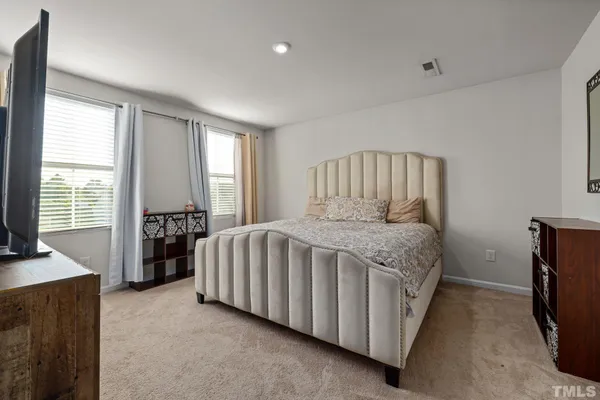 a bedroom with a bed and a flat tv screen on dresser