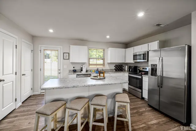 a kitchen with granite countertop a refrigerator and a stove top oven