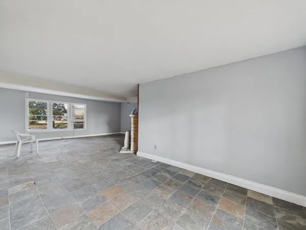 an empty room with windows and fireplace