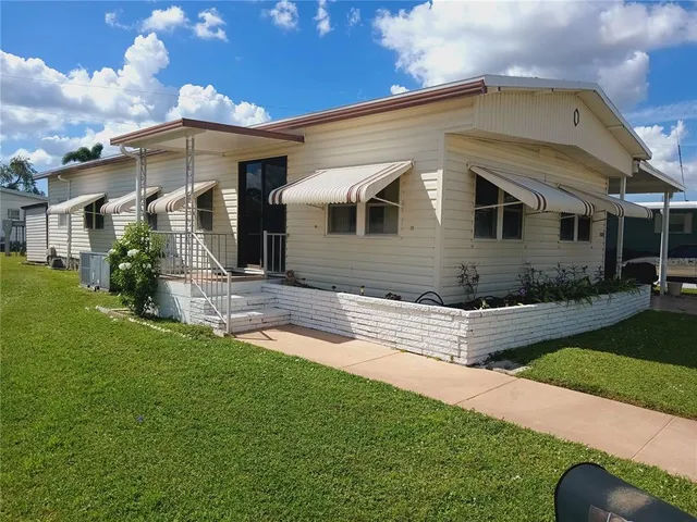a living room with furniture a couch and two large window