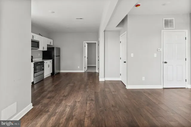 a view of a kitchen with wooden floor and a refrigerator