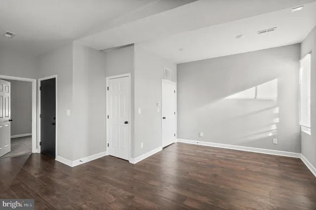 an empty room with wooden floor & windows