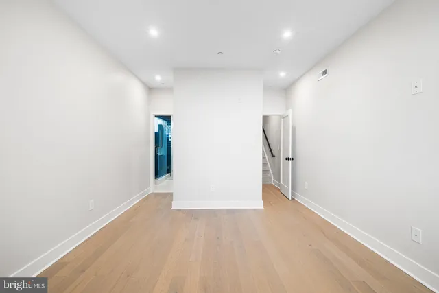 an empty room with wooden floor and entryway