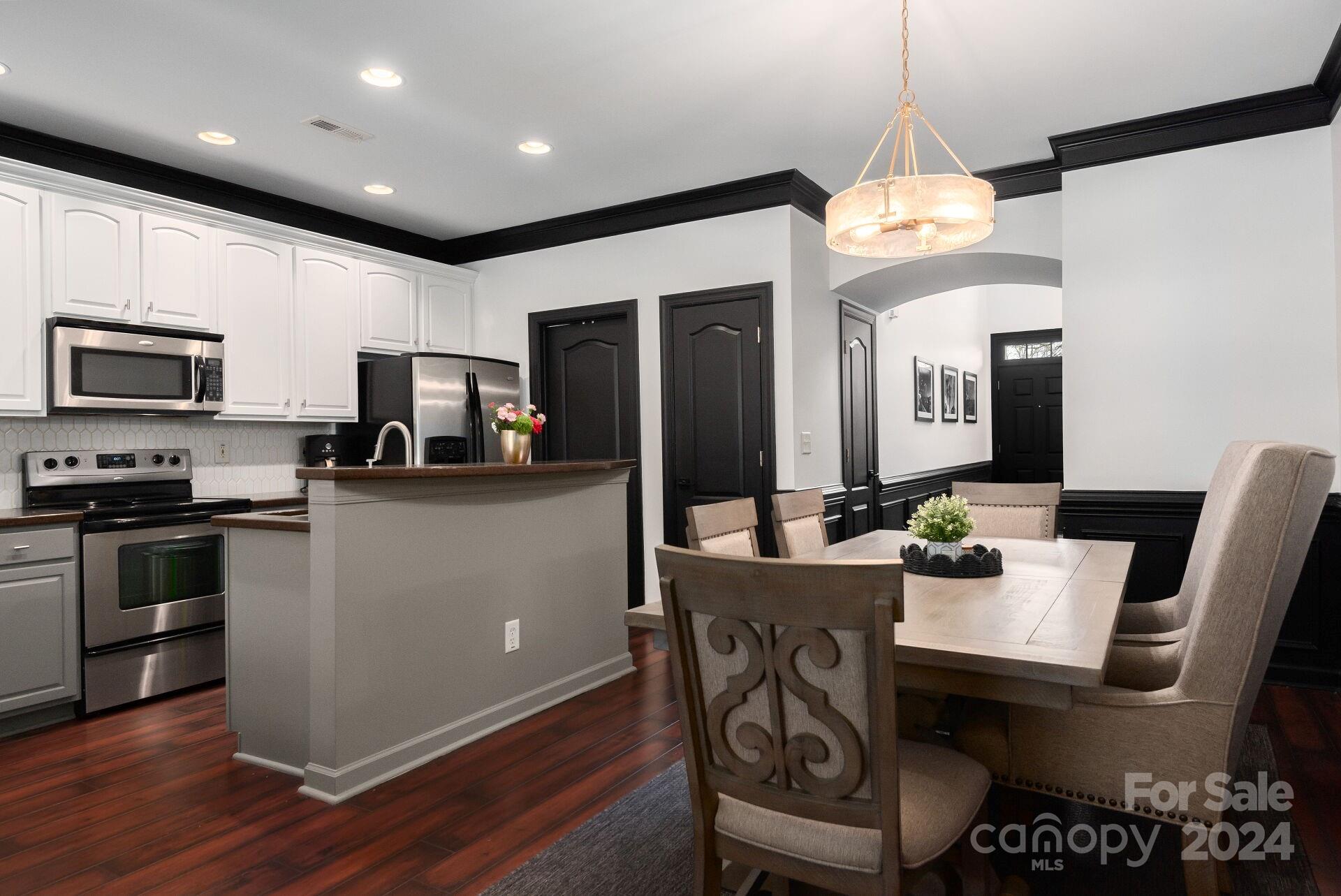 6725 Dusty Saddle Road Charlotte, NC 28277 - Photo 4 of 29 a kitchen with stainless steel appliances kitchen island granite countertop a stove top oven a sink a dining table and chairs with wooden floor