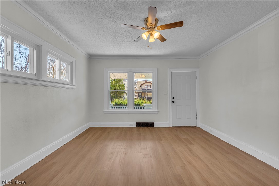 12905 Watterson Avenue Cleveland, OH 44105 - Photo 4 of 30 Unfurnished room featuring ceiling fan, light wood-type flooring, a textured ceiling, and crown molding