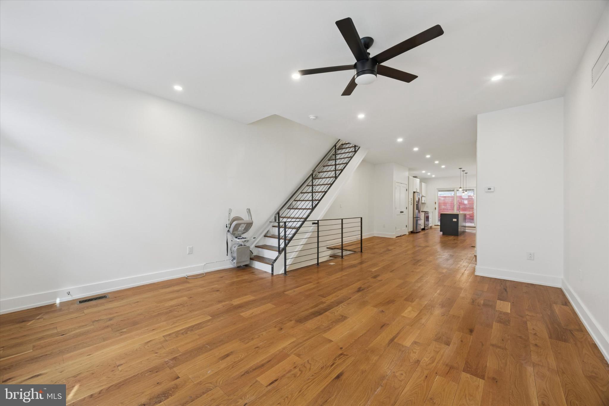 531 Mifflin Street Philadelphia, PA 19148 - Photo 4 of 28 an empty room with wooden floor a ceiling fan and staircase